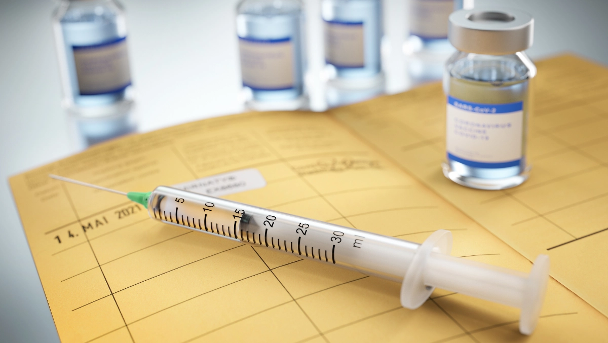 Impfpass mit Impfstoff und Nadel